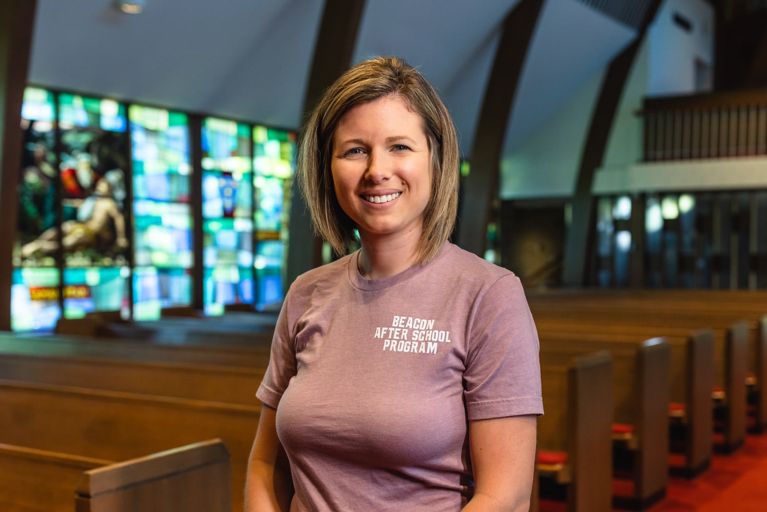 Melissa Keyser, wearing a purple shirt, standing in a church pew.